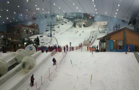 Family having fun in the snow park area of Dubai Ski Resort, featuring snow slides and snow play zones.